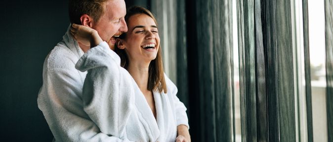 Ein Paar steht lachend vor einem Fenster