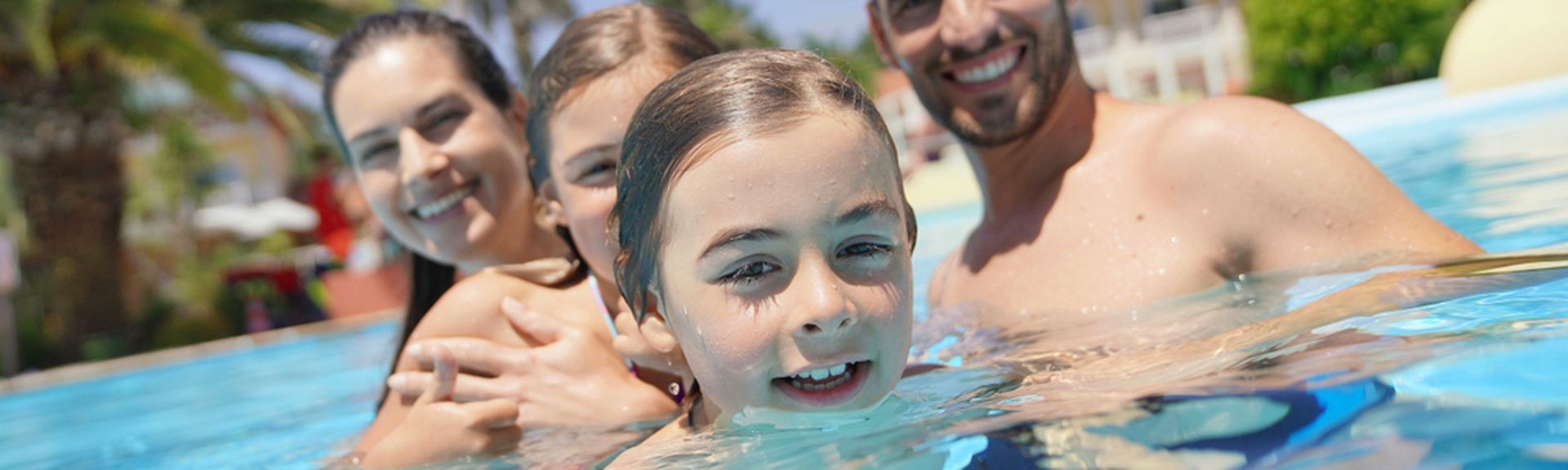 Eine Familie in einem Pool lächelt in die Kamera