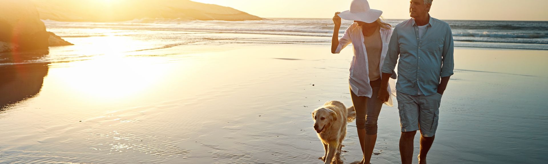 Ehepaar macht mit Ihrem Hund einen Spaziergang am Strand