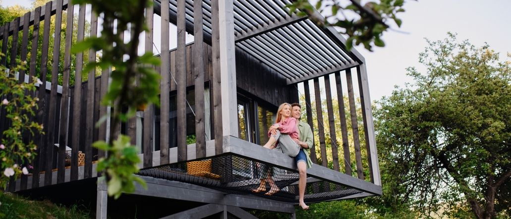 Eine Frau und ein Mann sitzen arm in Arm am Rand eines Hauses am Rand eines Hügels