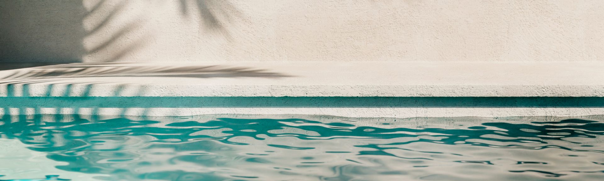 Poolwasser, auf der Wand im Hintergrund sieht man den Schatten einer Palme