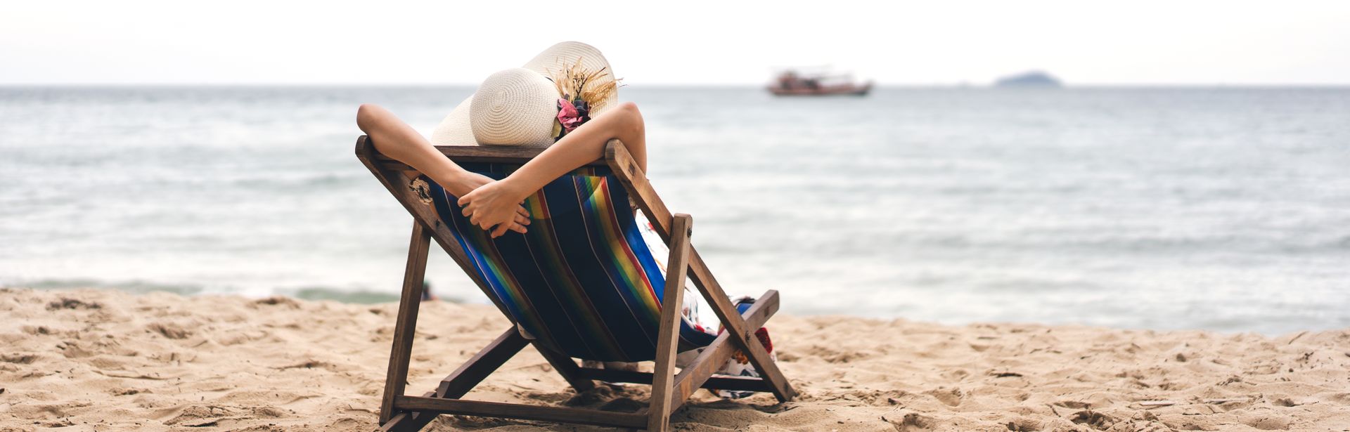 Person am Strand auf einer Liege schaut auf das Meer