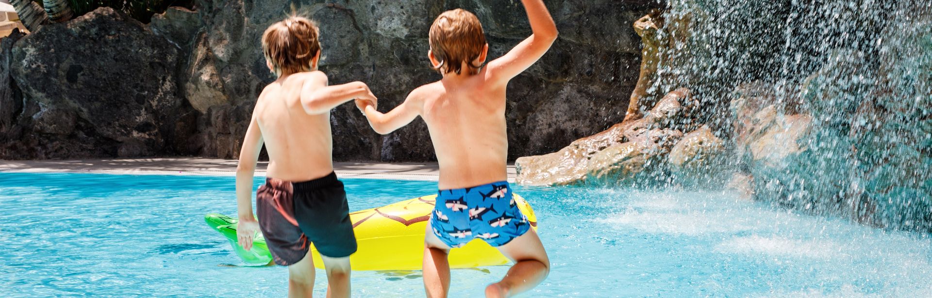 Zwei Jungs springen in einen Pool