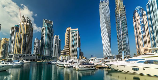 Hochhäuser ragen im Hintergrund empor. Im Vordergrund ist ein kleiner Hafen mit Yachten und kleineren Booten zu sehen