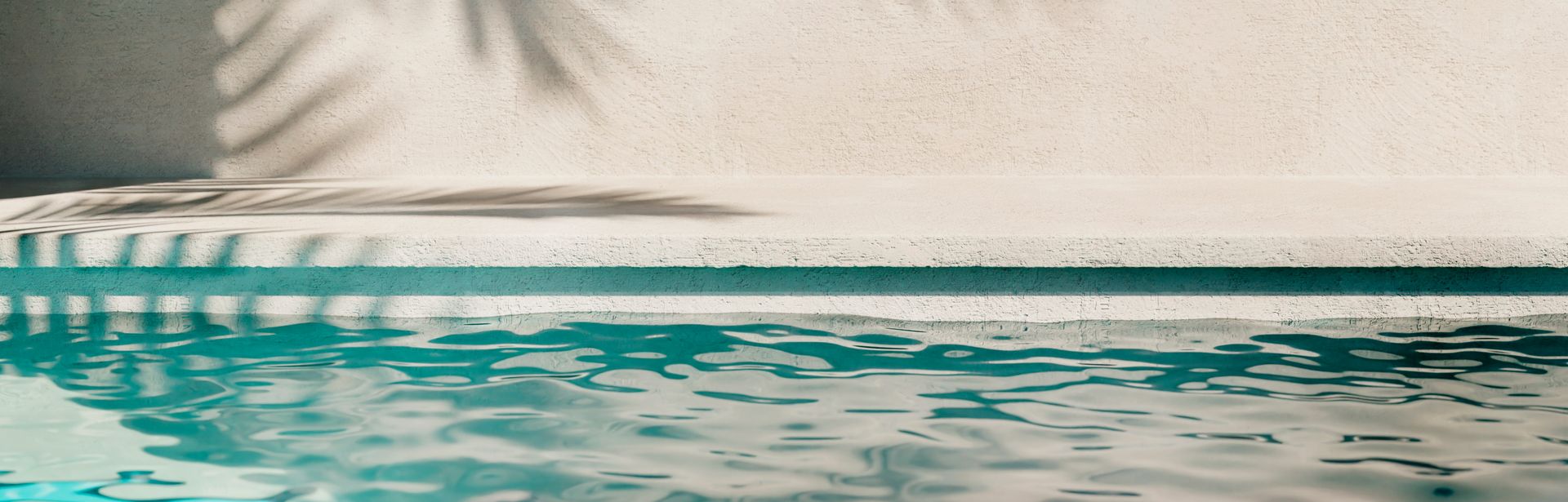 Poolwasser, auf der Wand im Hintergrund sieht man den Schatten einer Palme