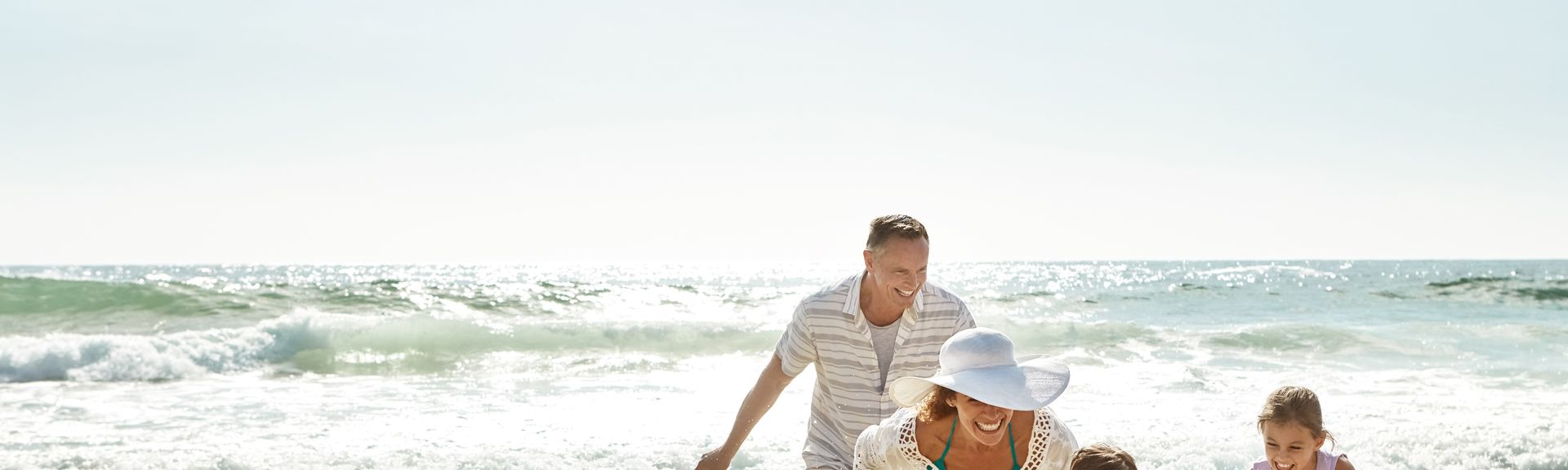 Eine Familie am Strand läuft lachend durch das Wasser