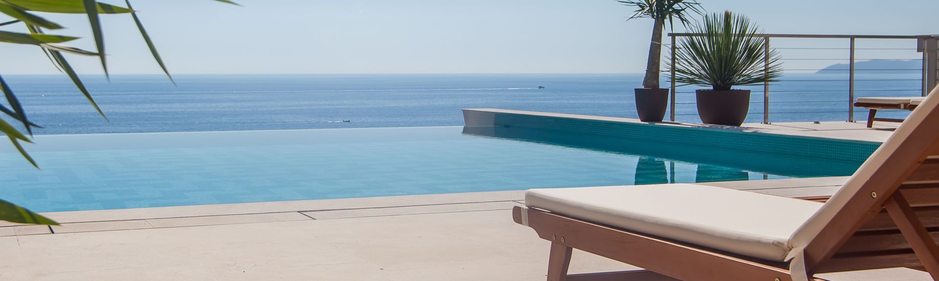 Eine Liege und an einem Infinity Pool, im Hintergrund das Meer