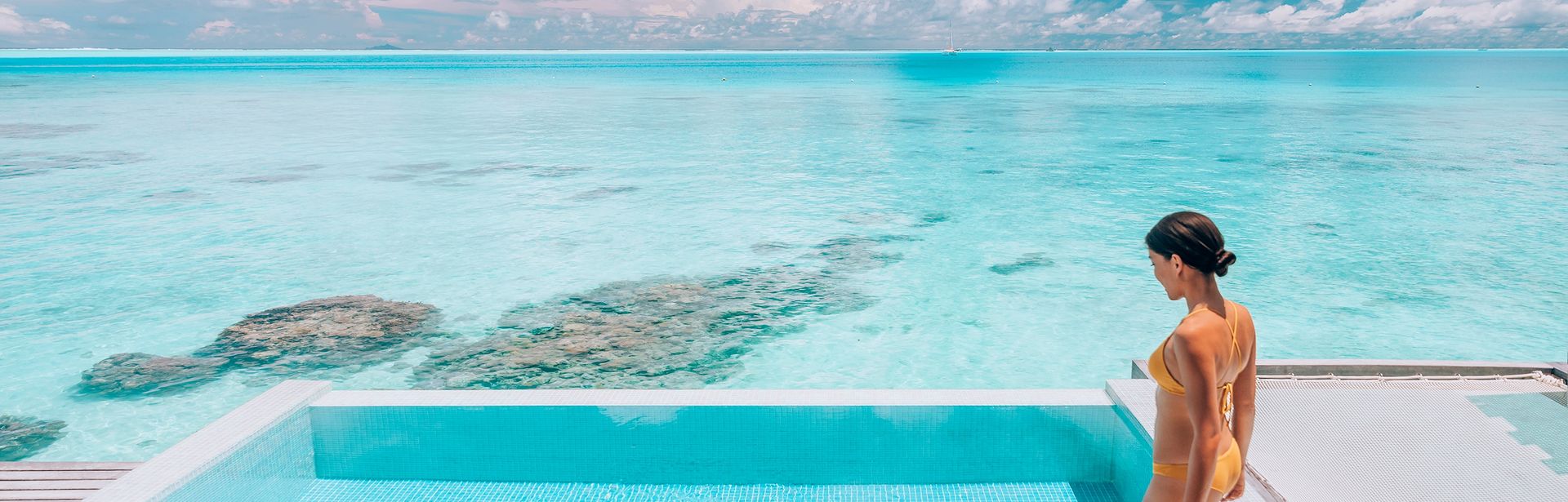 Eine Frau steigt in einen erhöht über dem Strand gelegen Pool
