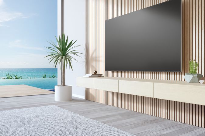 Fernseher in einem Hotelzimmer. Im Hintergrund ist ein Pool und das Meer zu sehen