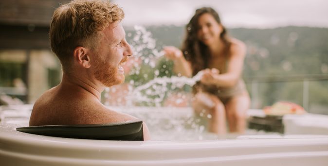 Zwei Personen im Whirlpool, die Frau macht den lachenden Mann nass