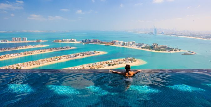 Eine Frau schaut aus einem Infinity Pool auf das Meer
