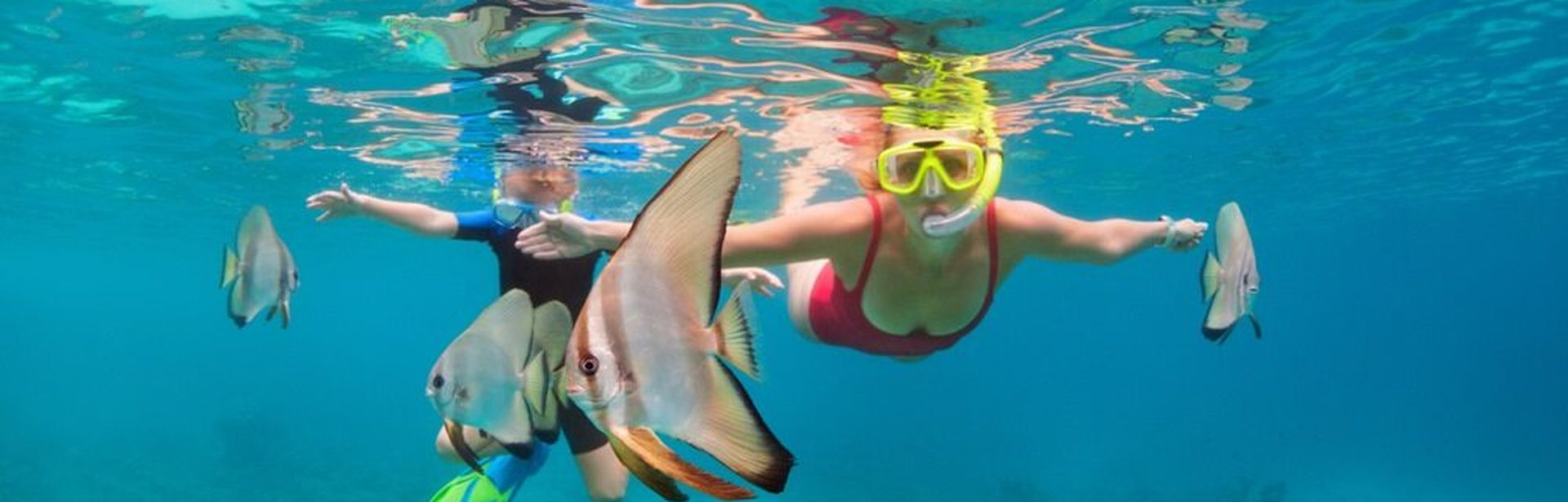 Zwei Kinder tauchen mit Taucherbrille und Schnorchel zwischen Fischen