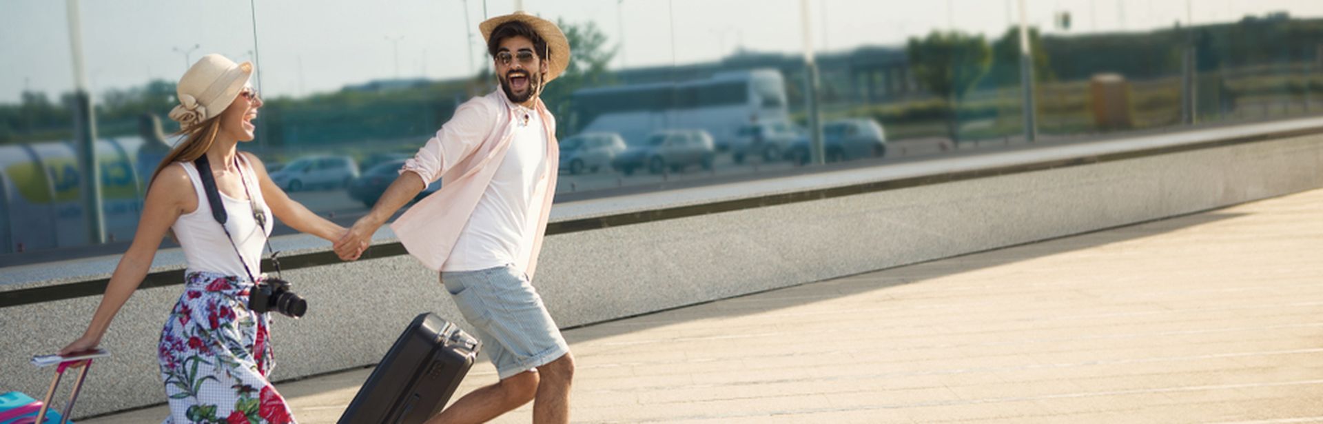 Ein Paar läuft mit Koffern aufgeregt einen Weg entlang