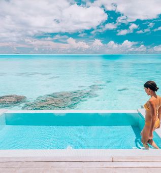 Eine Frau steigt in einen erhöht über dem Strand gelegen Pool