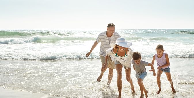 Eine Familie am Strand läuft lachend durch das Wasser
