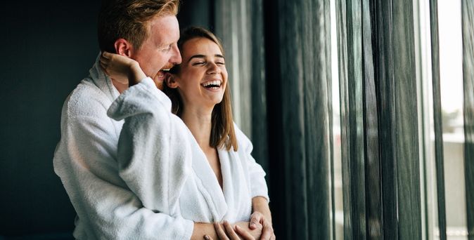 Ein Paar steht lachend vor einem Fenster