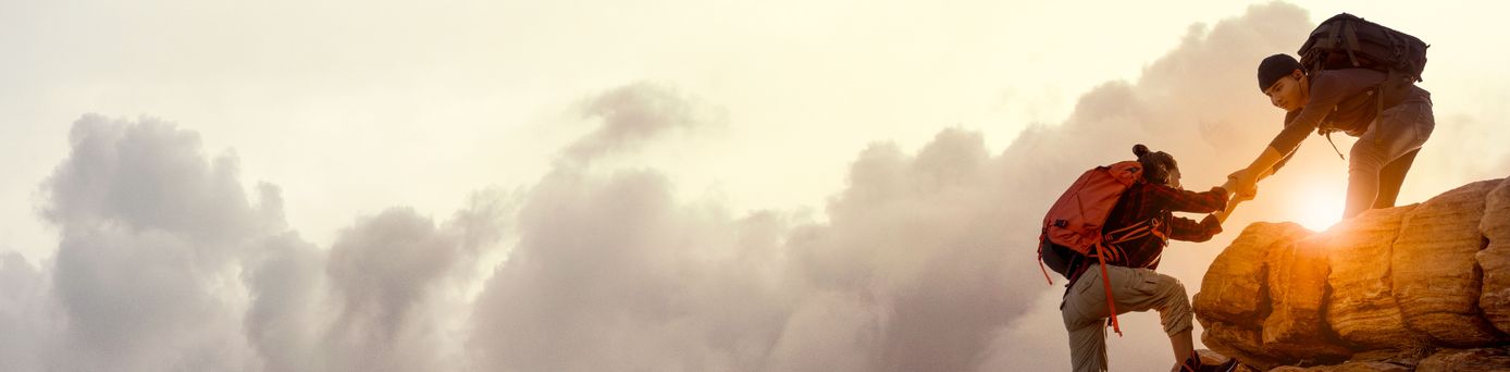 Wanderer bei Sonnenaufgang, Mann hilft Frau einen Berg hoch