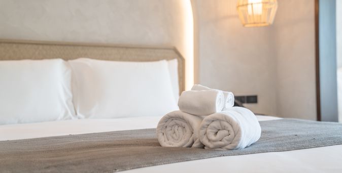 Aufgerollte Handtücher auf einem gemachten Bett