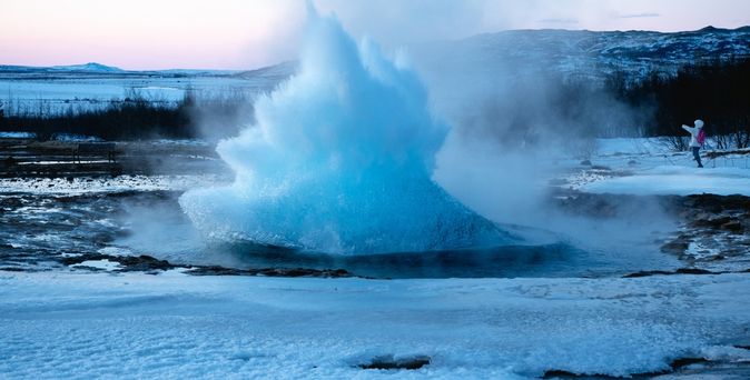 Ein ausbrechender Geysir in winterlicher Landschaft