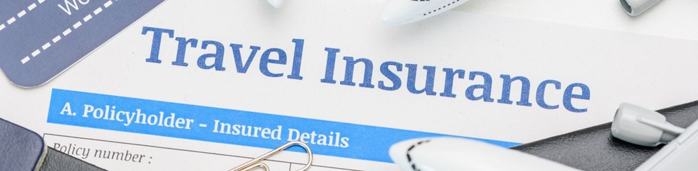 In der Mitte des Bildes steht "Travel Insurance" darum liegen mehrere Büroklammern, Reisepässe und mehrere kleine Flugzeuge