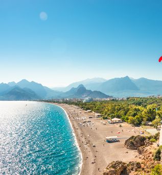 Paragleiter fliegt über einen Strand in der Türkei