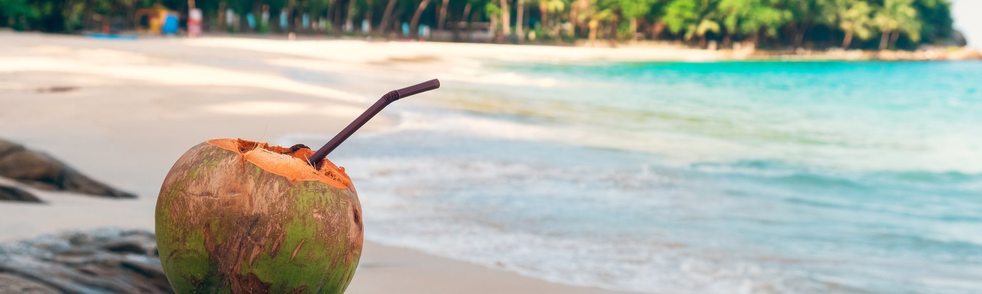 Kokosnuss mit einem Strohhalm steht am Strand