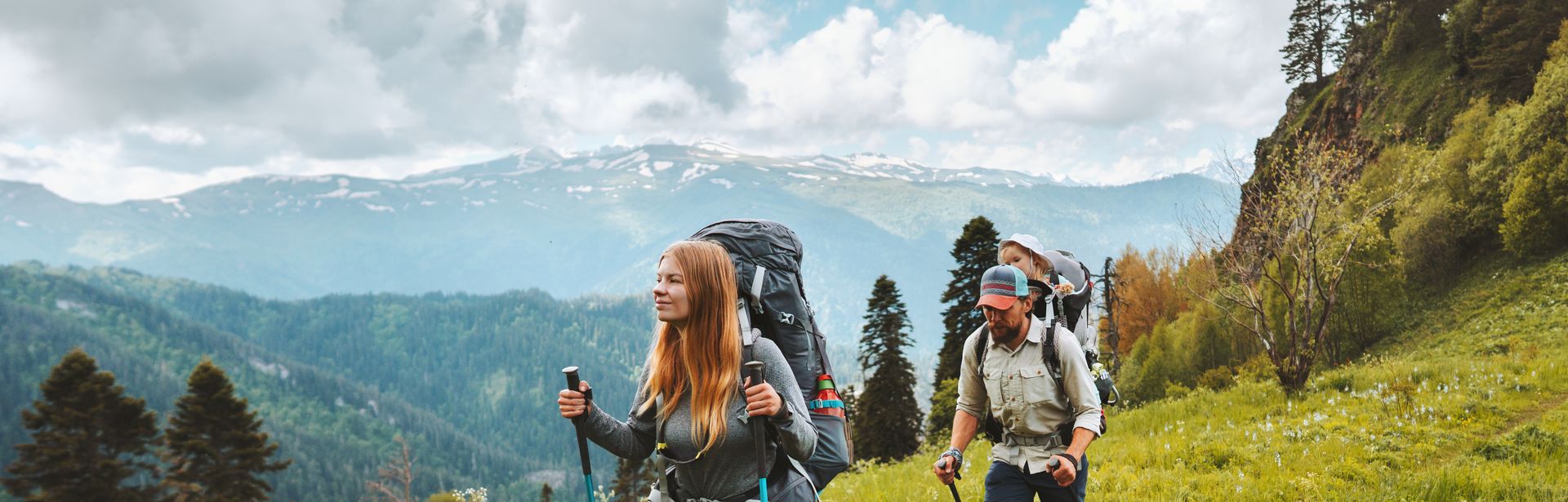 Zwei Personen wandern mit Nordic Walking Stöckern durch eine Wiese