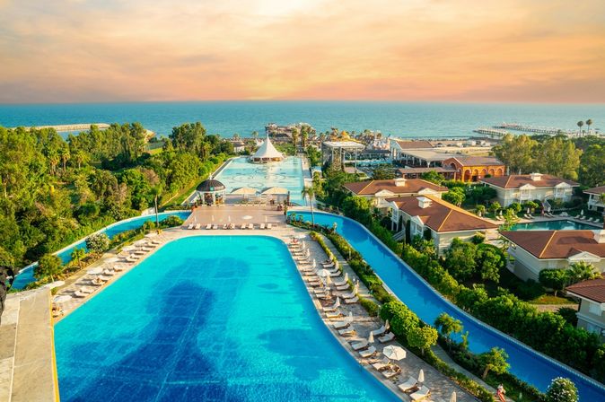 Zwei große Pools umgeben von Bäumen und mit Blick auf das Meer