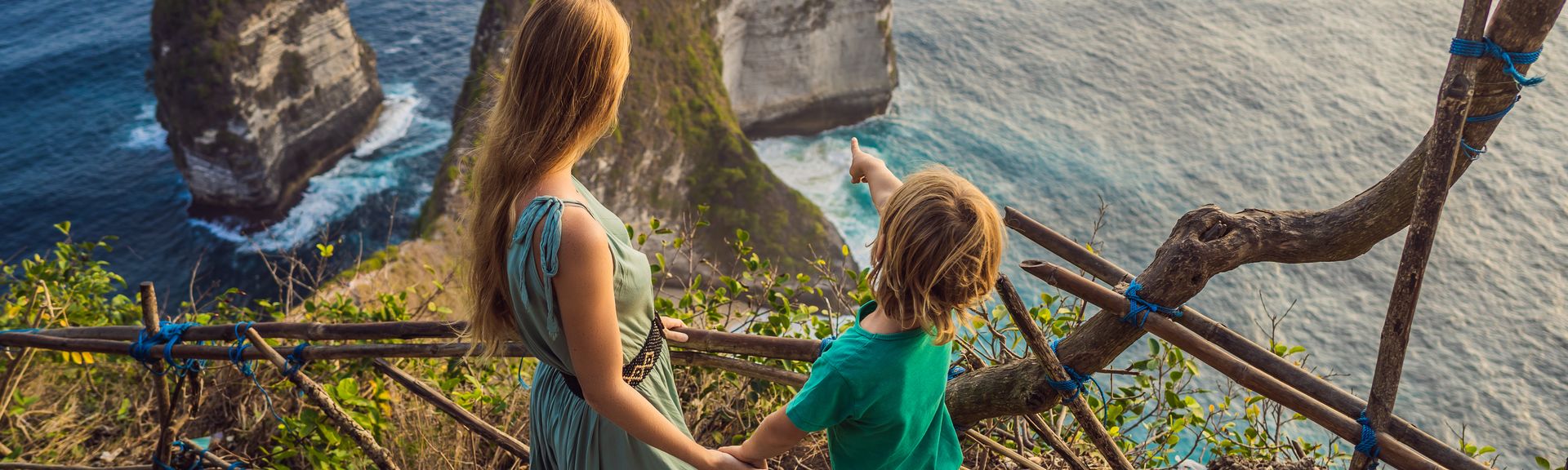 Mutter und Kind schauen von einer Treppe aus auf das Meer