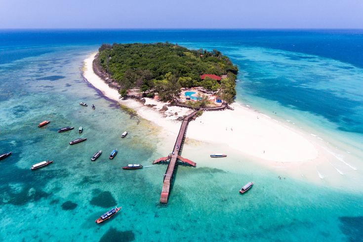 Eine kleine Insel mit Steg ins Meer, um die Insel herum schwimmen viele Boote