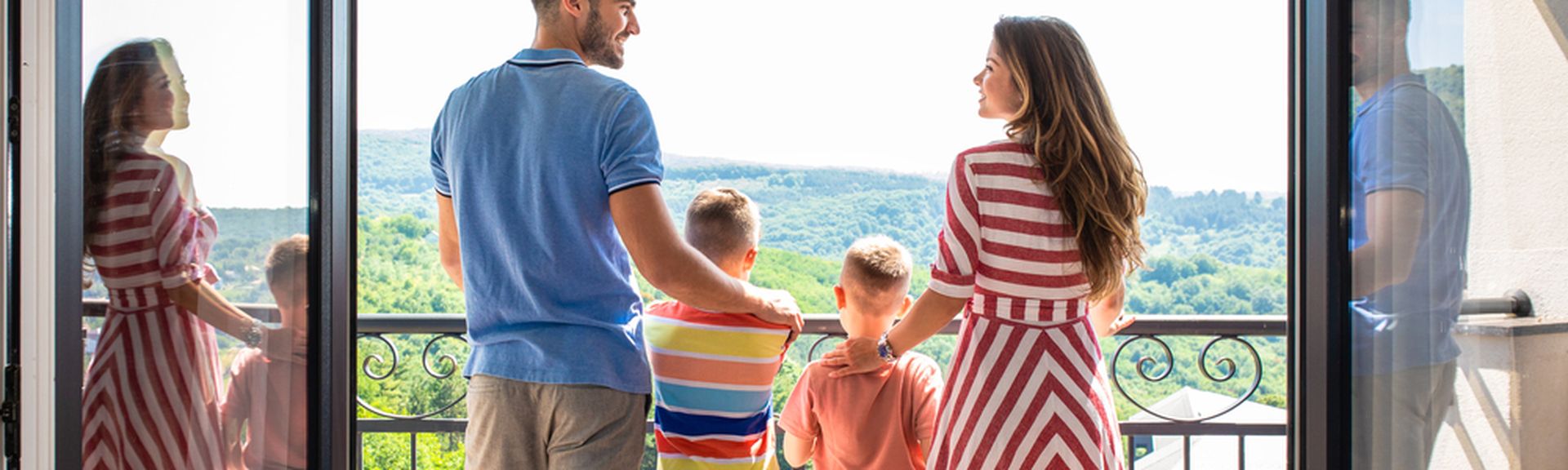 Eine Familie mit zwei Kindern steht Arm in Arm auf einem Balkon 