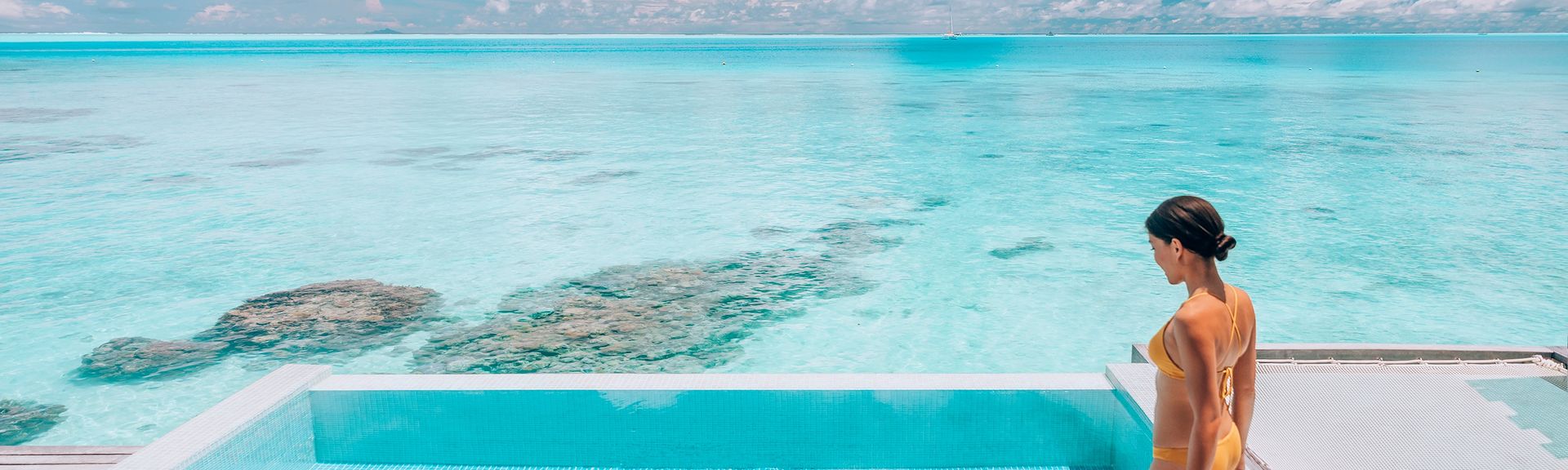 Eine Frau steigt in einen erhöht über dem Strand gelegen Pool