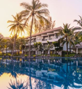 Ein großer Pool umgeben von Palmen bei Sonnenuntergang