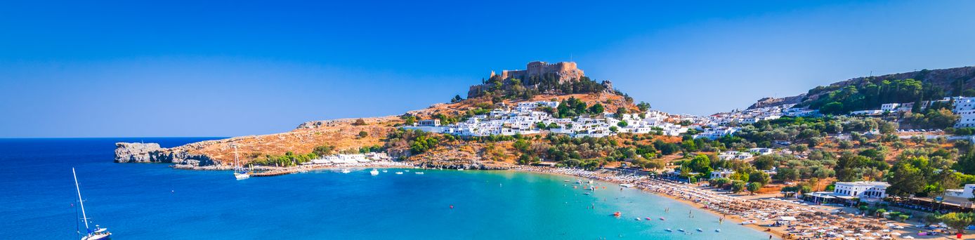 Bucht in Griechenland mit Strand und einer Stadt im Hintergrund