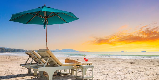Zwei Liegen mit Sonnenschirm stehen am Strand