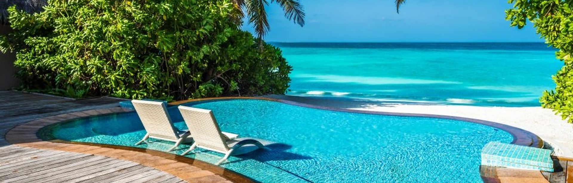 Ein kleiner Pool mit direktem Strandzugang und zwei Liegen