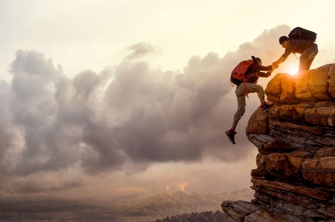 Wanderer bei Sonnenaufgang, Mann hilft Frau einen Berg hoch