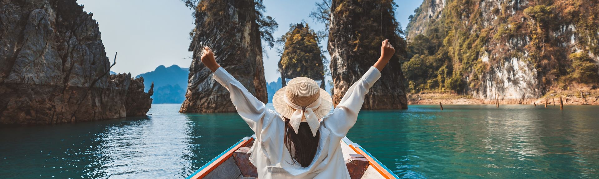 Alleinreisende Frau in einem Boot auf dem Wasser in Thailand