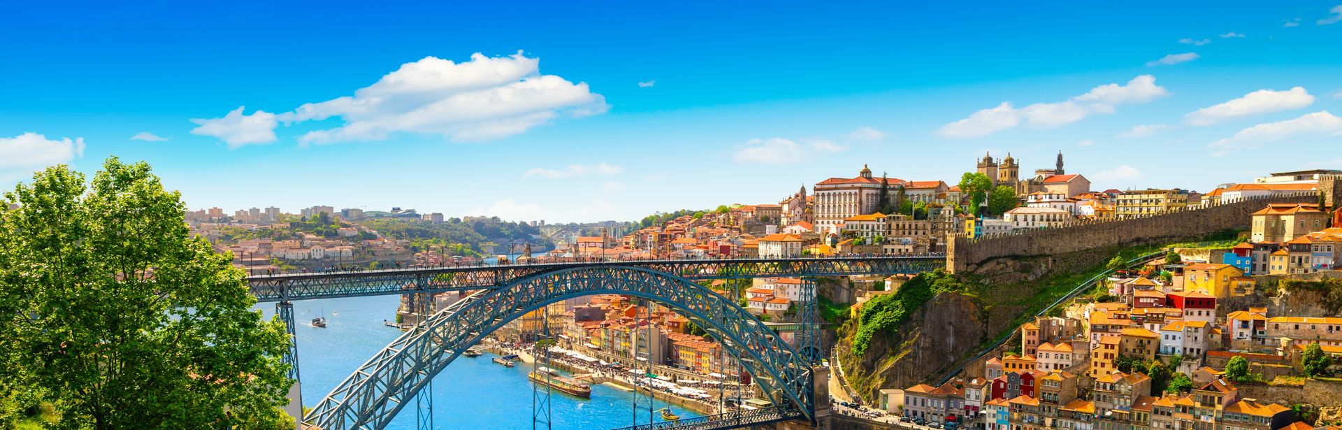 Brückenkonstruktion über einem Fluss. Direkt am Fluss ist auf beiden Seiten eine Stadt