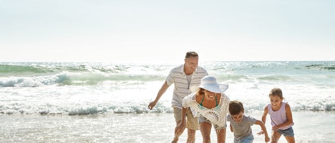 Eine Familie am Strand läuft lachend durch das Wasser