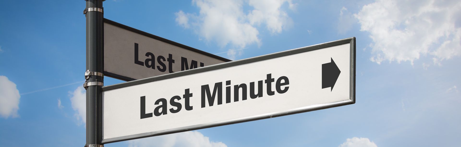 Ein Wegweiser mit zwei Schildern, auf beiden steht "Last Minute" mit einem Pfeil