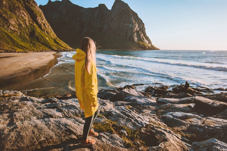 Eine Frau in einer gelben Regenjacke schaut auf das Meer