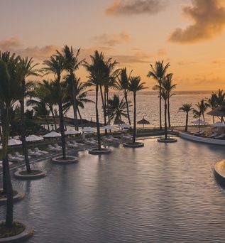 Hotel mit Poollandschaft direkt am Meer bei Sonnenuntergang