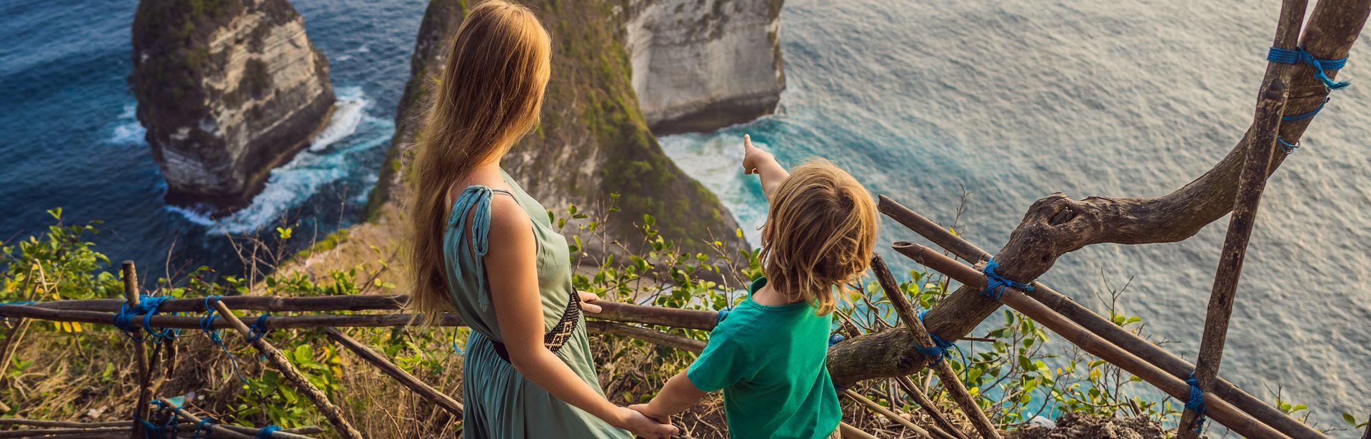 Mutter und Kind schauen von einer Treppe aus auf das Meer