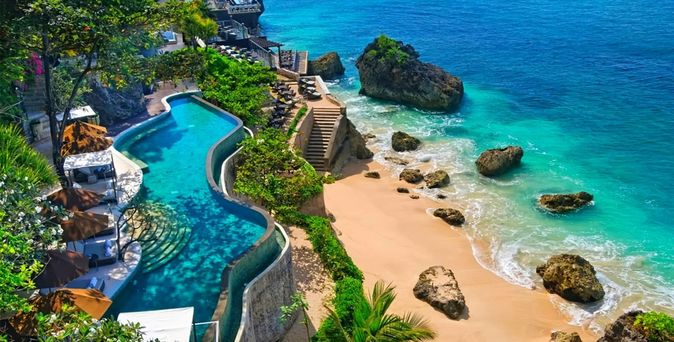 Infinity-Pool auf einer Terrasse oberhalb des Strandes. Unterhalb führt eine Treppe direkt zum Meer