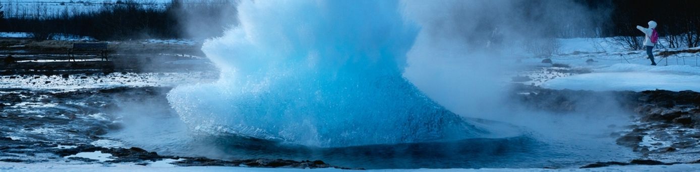 Ein ausbrechender Geysir in winterlicher Landschaft