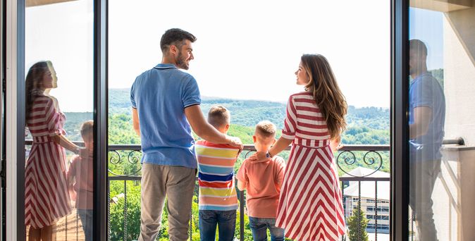 Eine Familie mit zwei Kindern steht Arm in Arm auf einem Balkon 
