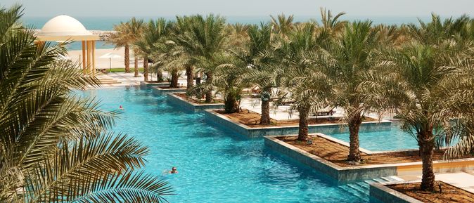 Poollandschaft mit Palmen und Blick auf das Meer