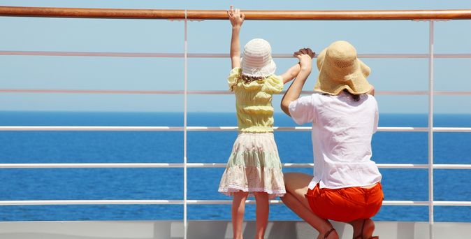 Mutter und Kind stehen an der Reling von einem Kreuzfahrtschiff und schauen auf das Meer