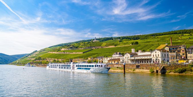 Flusskreuzfahrtschiff auf einem Fluss, der durch eine grüne Landschaft führt